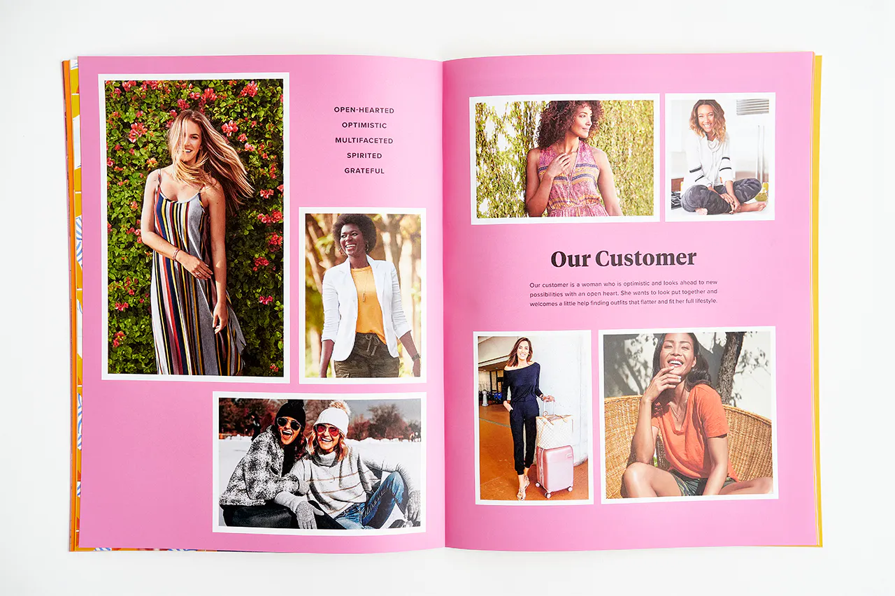 An Evereve brand book laying open to images of smiling women against a bright pink background.