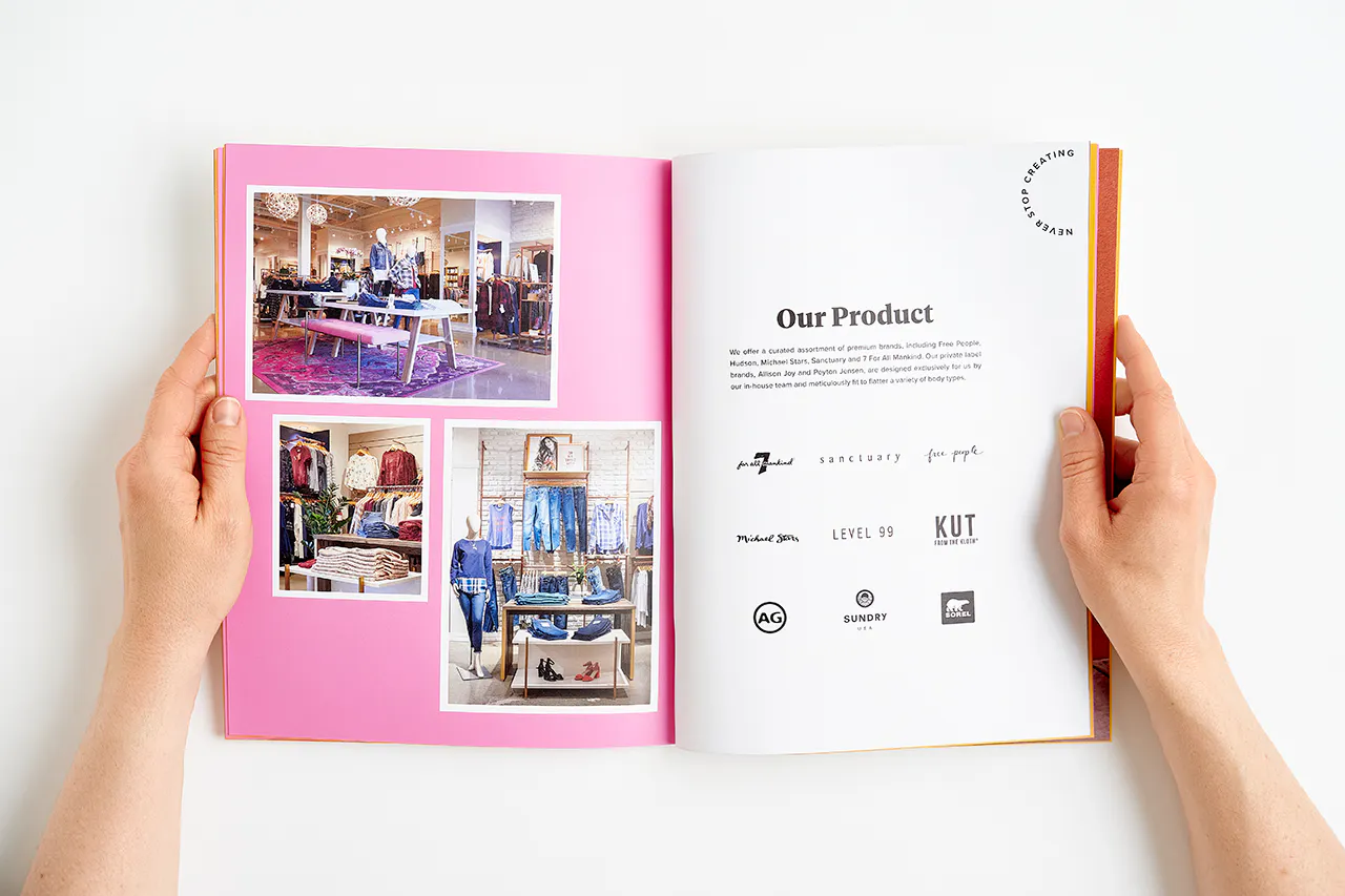 Two hands holding open an Evereve brand book to images of their retail store and Our Product in black.