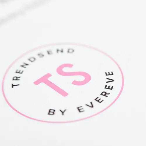 A round logo with a pink and black design and Trendsend by Evereve in the middle.