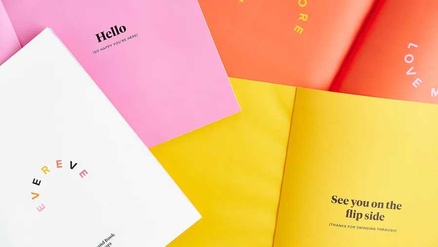 Four custom booklets laying open and overlapping each other with bright orange, pink and yellow pages.