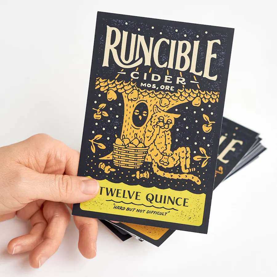 A hand holds a marketing postcard with Runcible Cider printed at the top above a stack of more postcards.