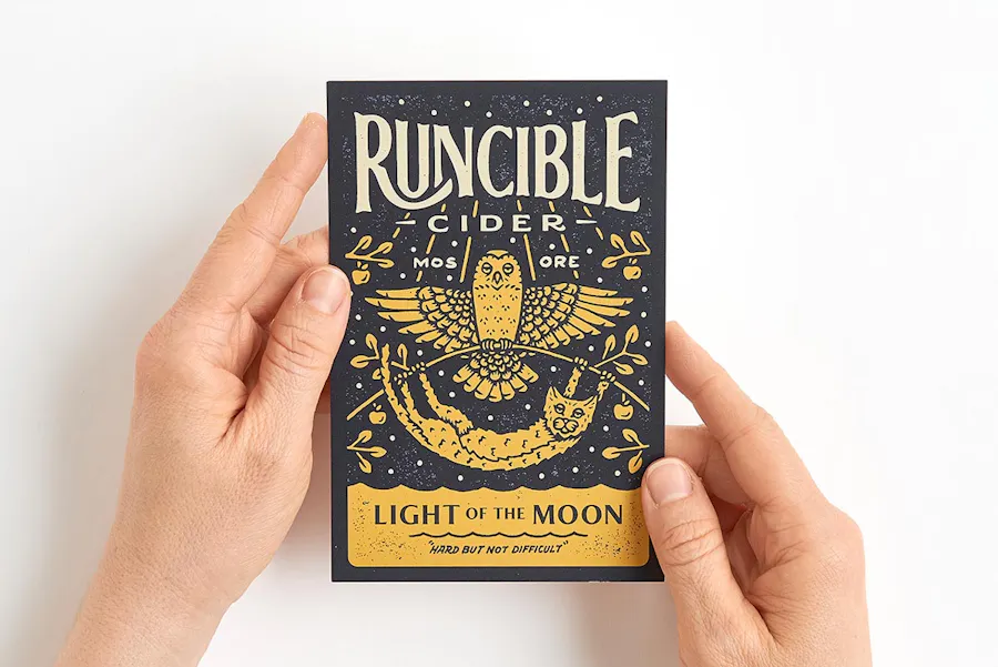 Two hands holding promotional postcards printed with Runcible Cider and an owl graphic on the front.