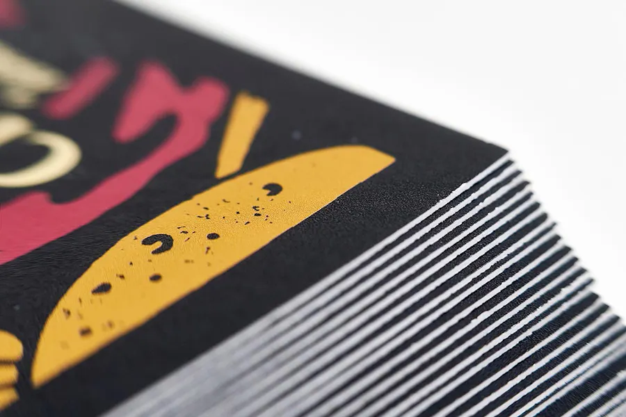 The corner of a stack of marketing postcards with a black, gold and red design.