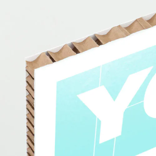 The corner of a honeycomb cardboard sign printed with a white and aqua design and a white letter Y.