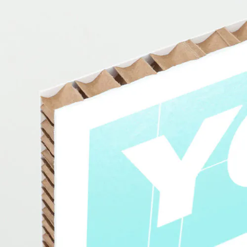Falconboard Core The corner of a honeycomb cardboard sign printed with a white and aqua design and a white letter Y.