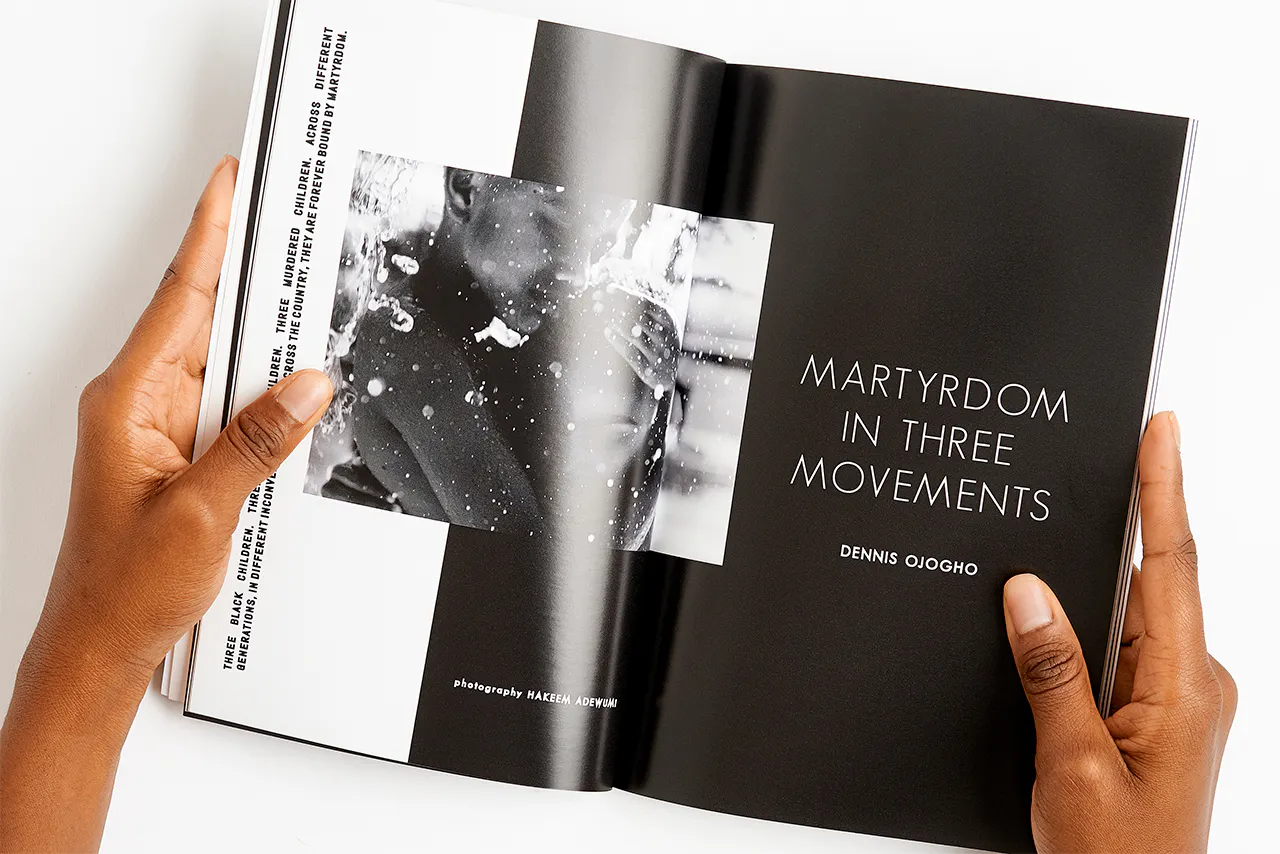 Two hands holding a magazine open to a black and white image of two people hugging and being splashed with water.