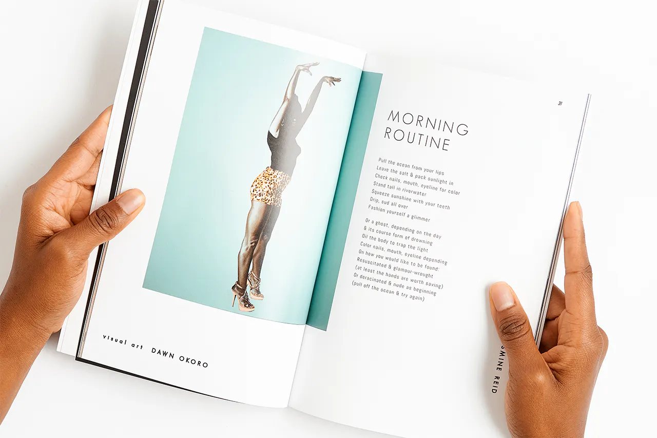 Two hands holding a magazine open to a woman wearing heels, shorts and a T-shirt raising her arms above her head.