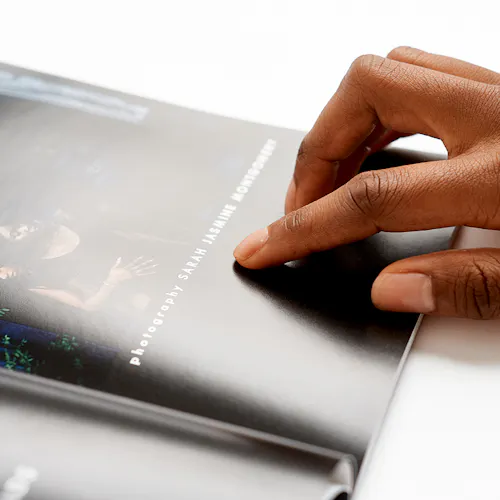 A handing laying on the right side of a magazine laying open to an image of three woman.