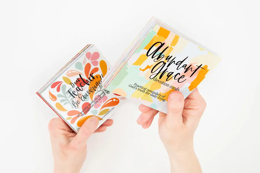 Two hands holding stacks of custom devotional cards created with collated printing.