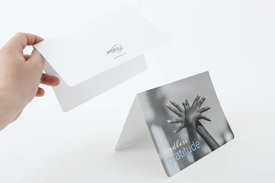 A hand holding a custom thank you card above another card standing open with endless gratitude on the front.