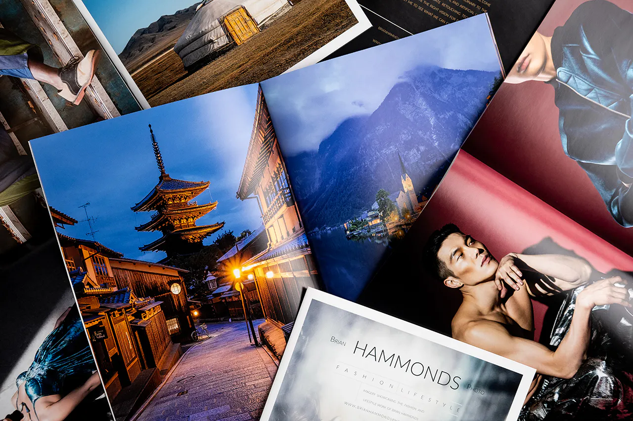 A pile of photography books laying open to images of a man, a pagoda, mountains and a rural round building.