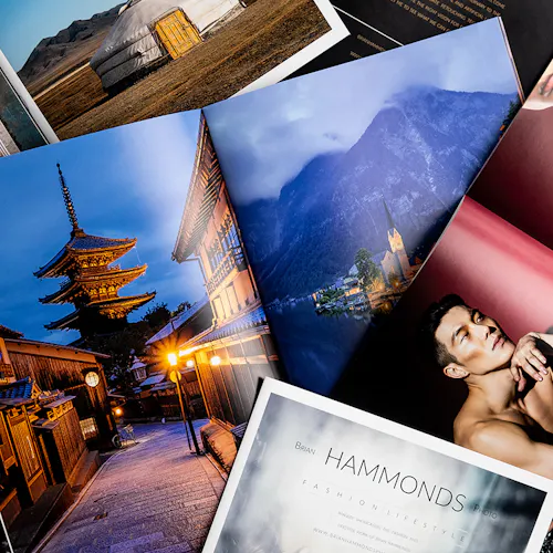 A pile of photography books laying open to images of a man, a pagoda, mountains and a rural round building.