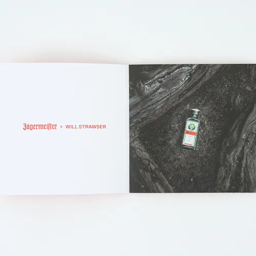 ©Will Strawser A photography book laying open to Jagermeister x Will Strawser in red and an image of a small bottle of alcohol on the ground.