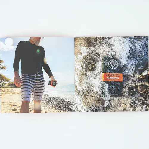 ©Will Strawser A photography portfolio laying open to a man in shorts on the beach and a bottle of alcohol laying in water on rocks.