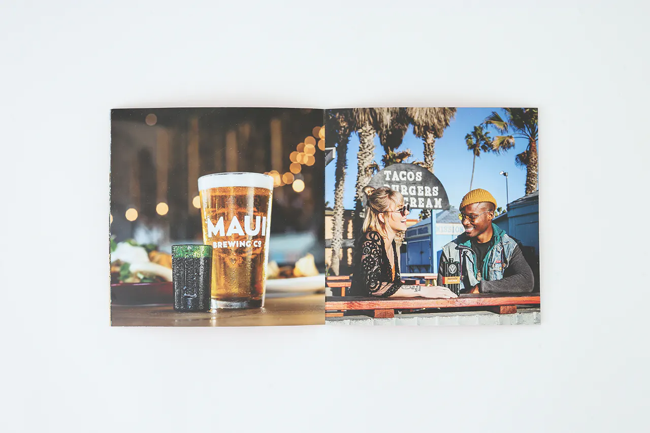A photo book laying open to images of a pint glass of beer and two people sitting at a table outside.