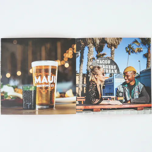 A photo book laying open to images of a pint glass of beer and two people sitting at a table outside.