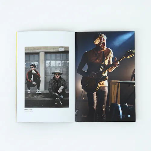 A portfolio laying open to images of a man playing guitar and two men sitting in front of a garage door.