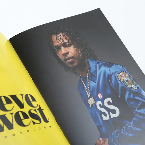 A photography booklet laying open to an image of a man in a blue jacket and Steve West on a yellow background.