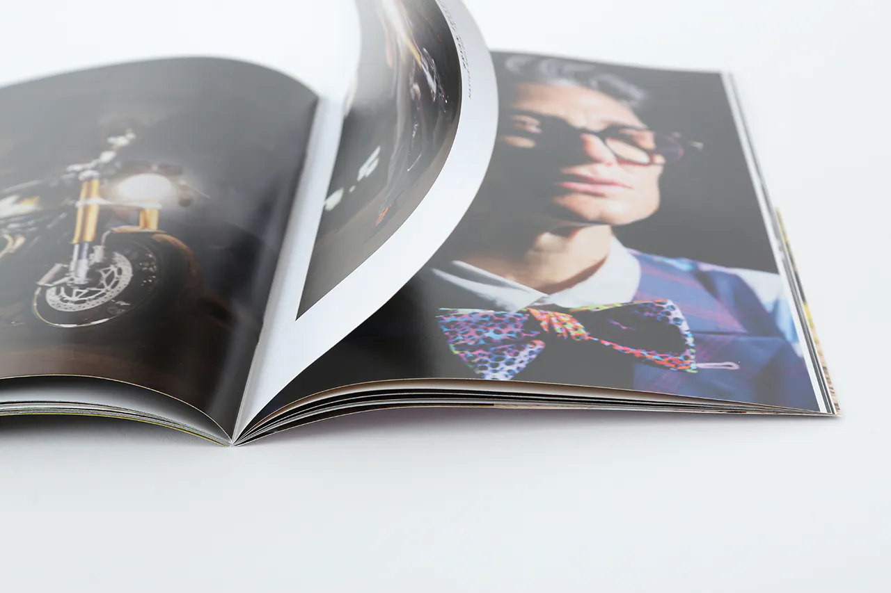 A photography portfolio laying open to images of a person wearing glasses and a bowtie.