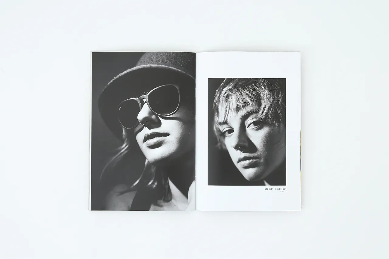 A portfolio laying open to black and white images of a woman wearing a hat and sunglasses and one with a nose ring.