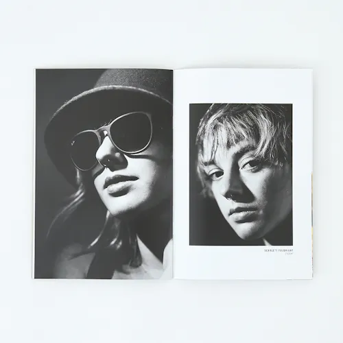 A portfolio laying open to black and white images of a woman wearing a hat and sunglasses and one with a nose ring.