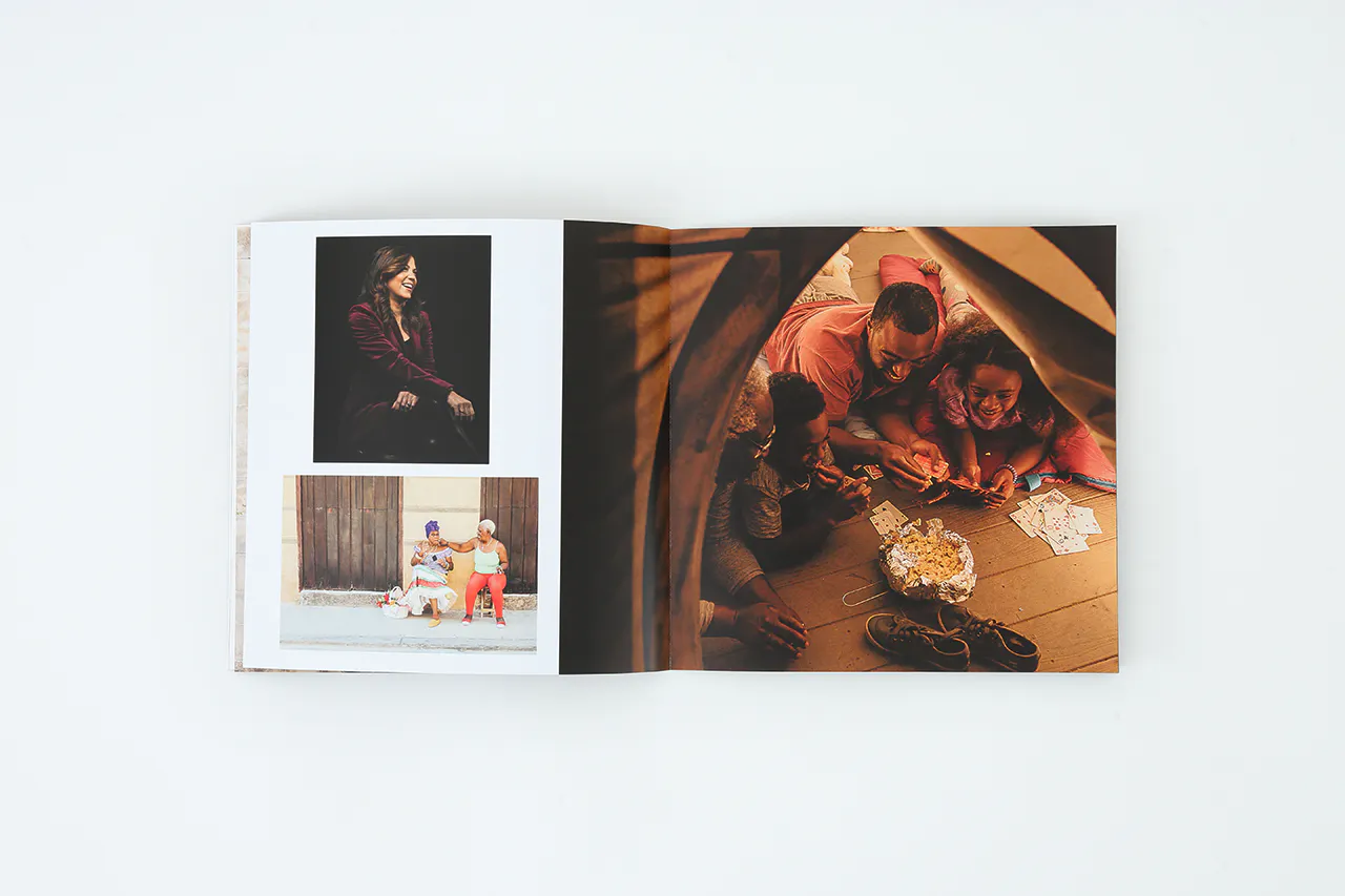 A photo portfolio laying open to images of a family eating popcorn in a tent and two people sitting on the street.