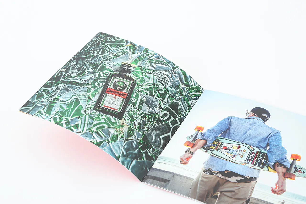 A photography lookbook laying open to images of a bottle of alcohol and a person holding a skateboard behind their back.