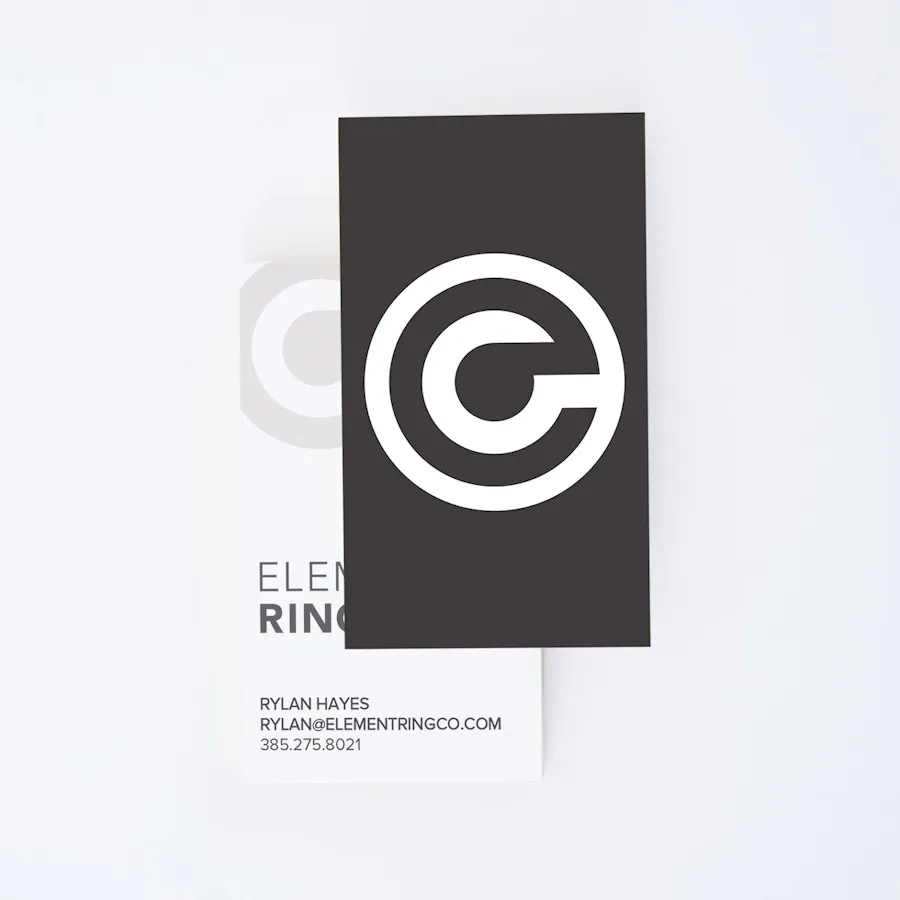 Two unique business cards overlapping each other with round logo on black on the front and contact info on the back.