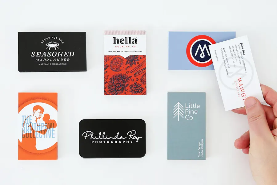 A collection of unique business cards printed with custom designs and colors and a hand holding one.