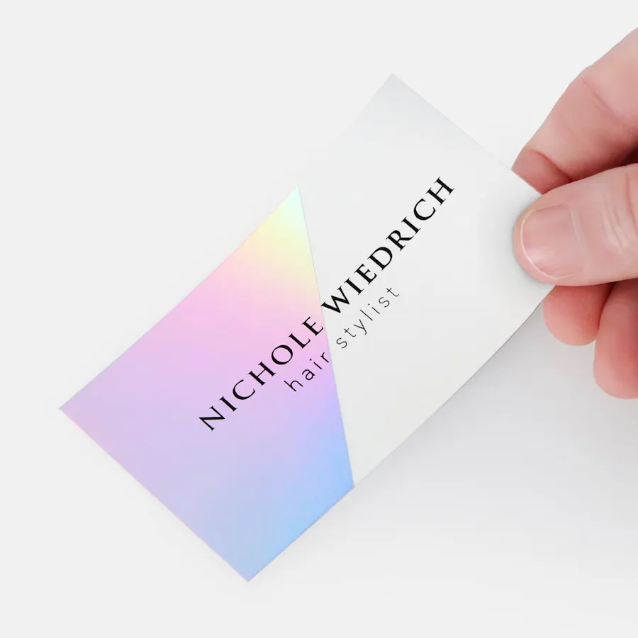 A hand holding a custom business card printed with holographic foil.