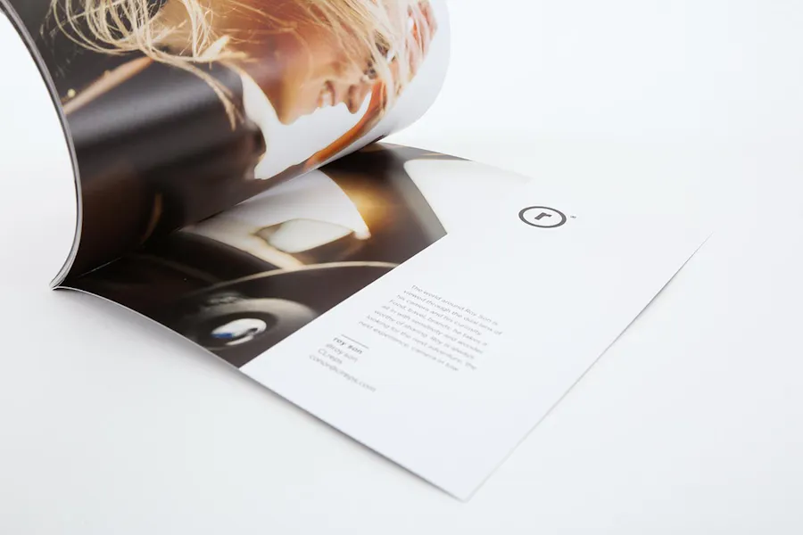 A photography portfolio with a perfect binding open to an image of a woman smiling in a car.
