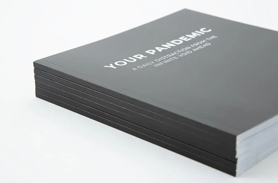 A stack of custom booklets printed with a perfect binding and a black cover with Your Pandemic in white.