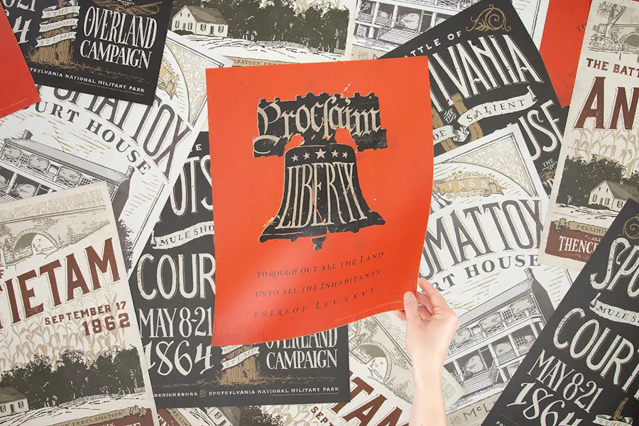 A hand holding a custom poster with Proclaim Liberty and an orange background above a collage of more custom posters.