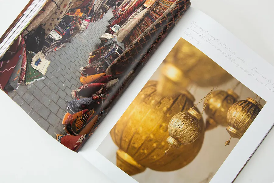 A photography lookbook laying open to images of a rugs at an outdoor market and gold lamps.