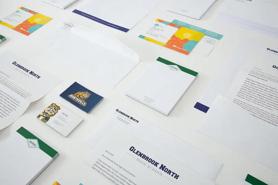 Custom school supplies laid out in rows, including printed notepads, direct mail letters and postcards.