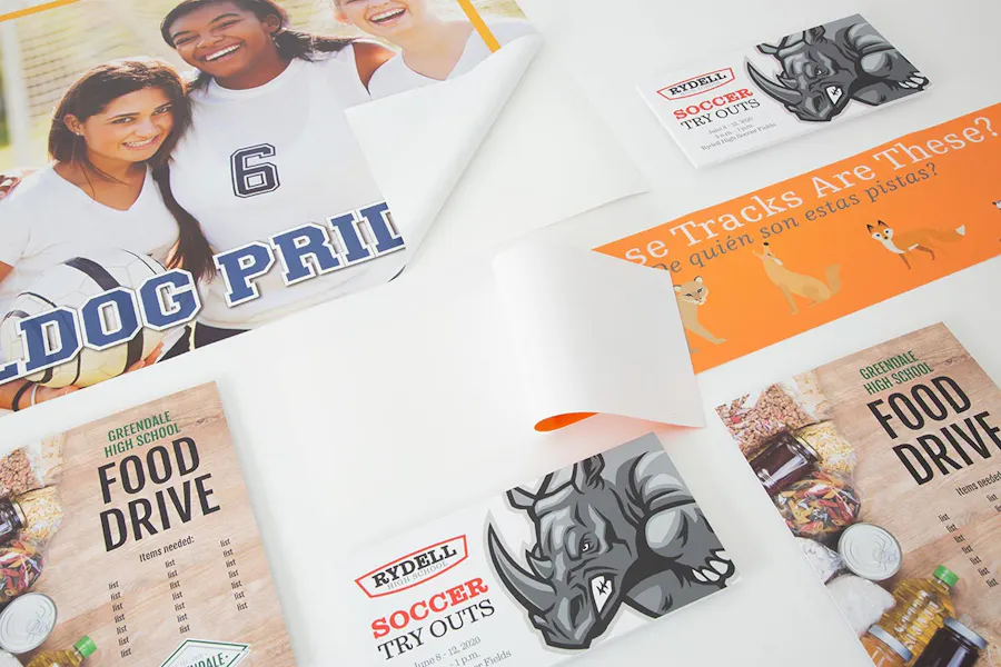 Various school print marketing materials, including food drive posters, soccer tryout flyers and wall decals.