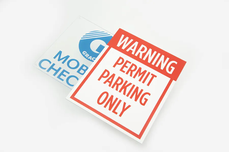 A permit parking sign in red and white laying on top of a clear parking sign with Mobile Checkin in blue text.