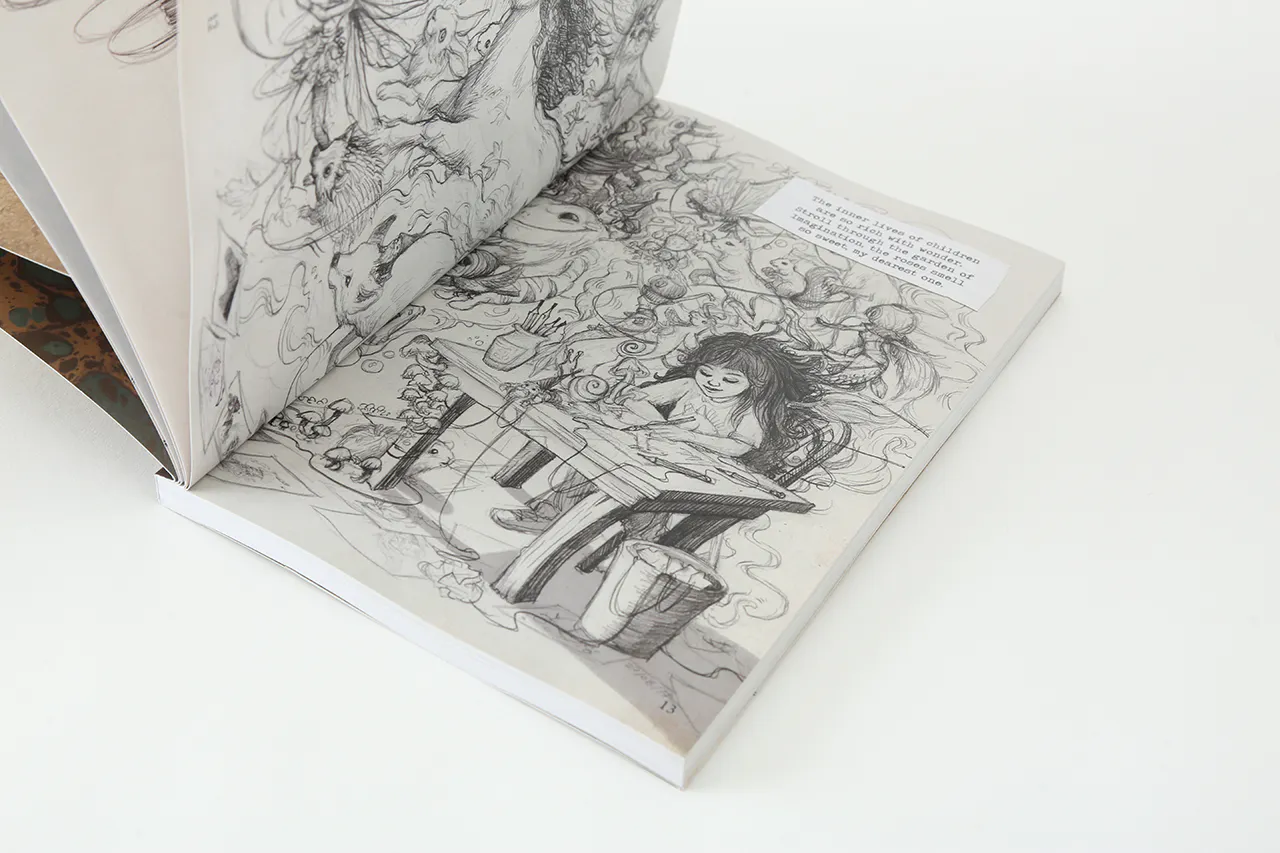 A sketchbook laying open to illustrations of a young girl sitting at a desk and drawing.