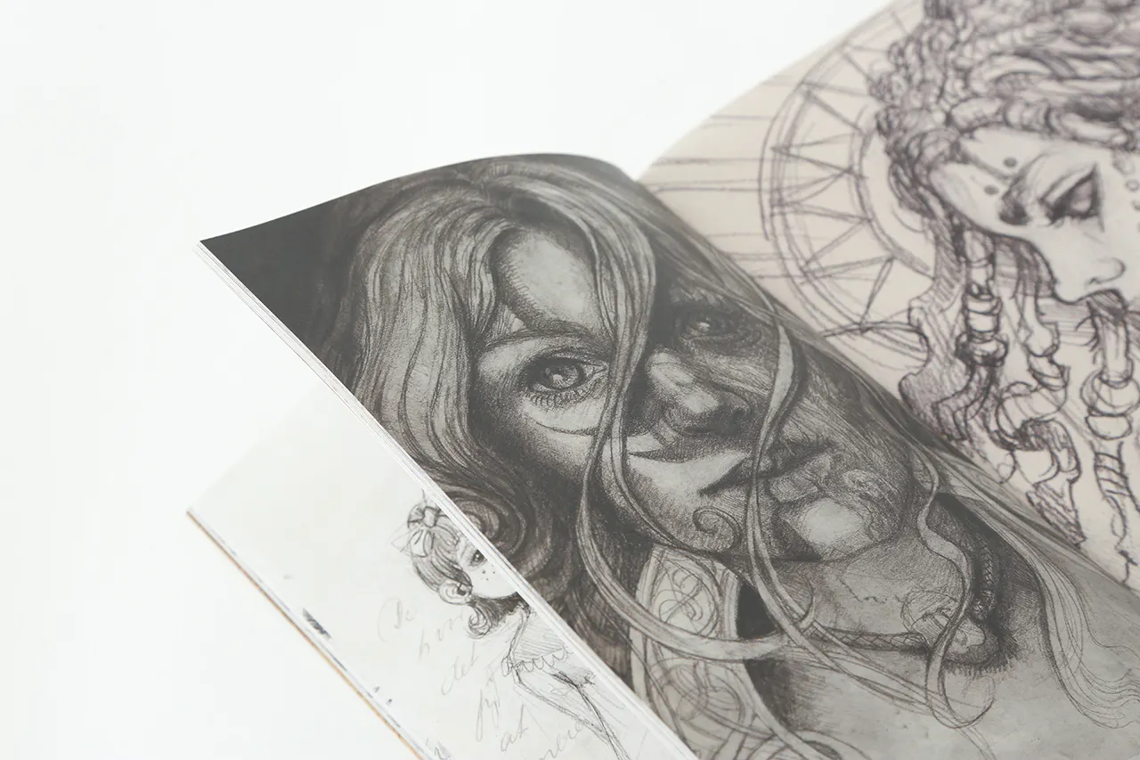 A sketchbook laying open to an illustration of a woman with hair blowing in her face.