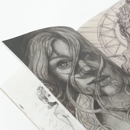 A sketchbook laying open to an illustration of a woman with hair blowing in her face.