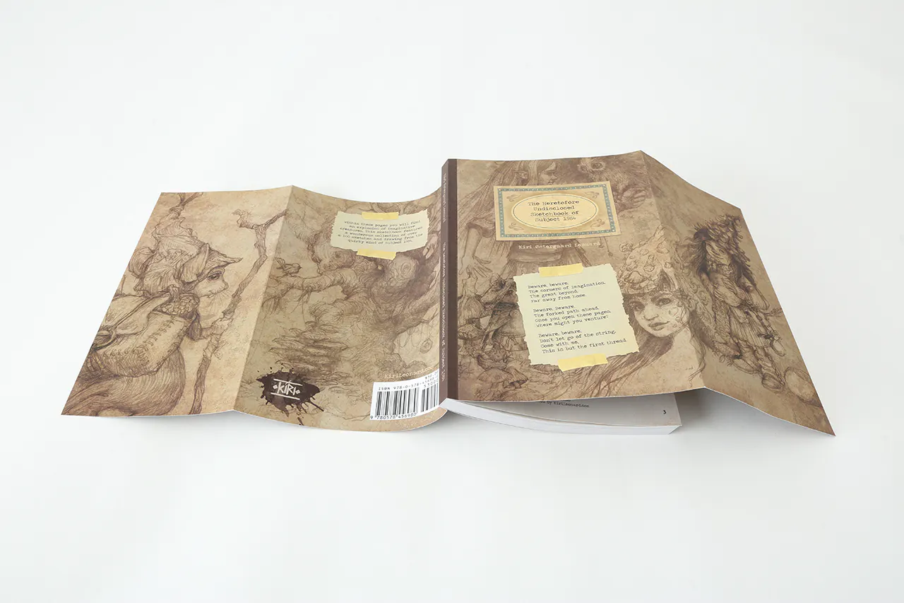 A sketchbook laying open with its spine up and a sepia-colored cover unfolded.