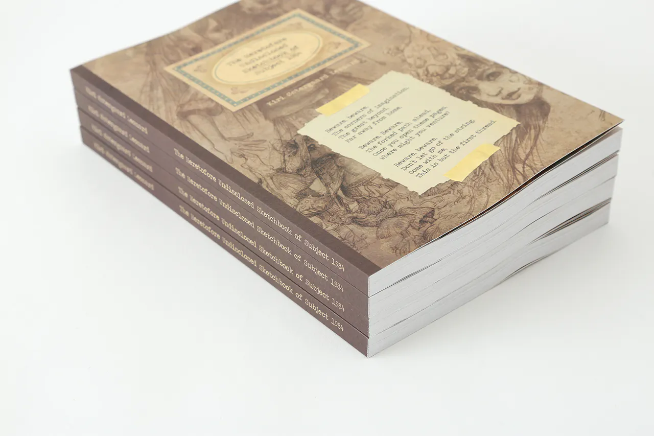 A stack of custom sketchbooks printed with a sepia-colored cover and a perfect binding.
