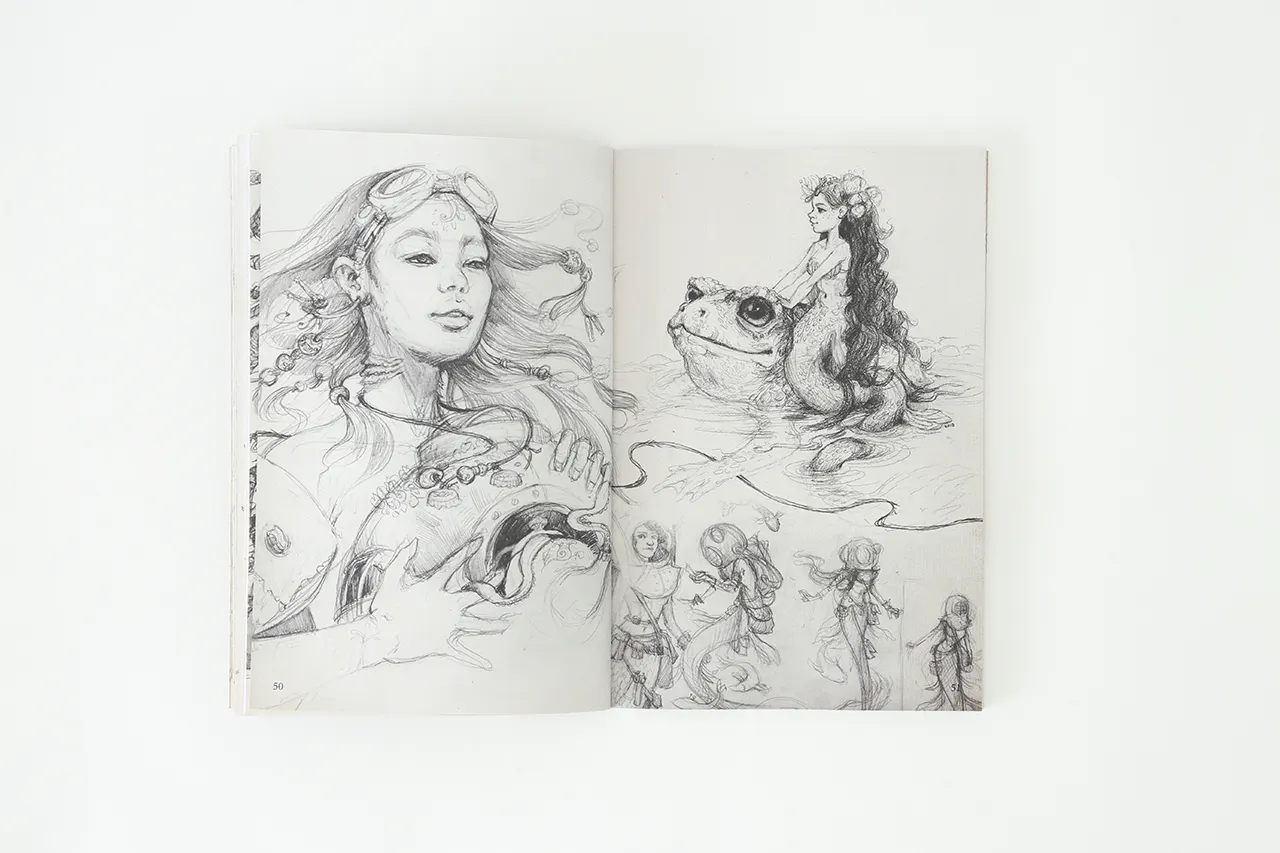A sketchbook laying open to illustrations of a woman with flowing hair and a girl sitting on a frog.