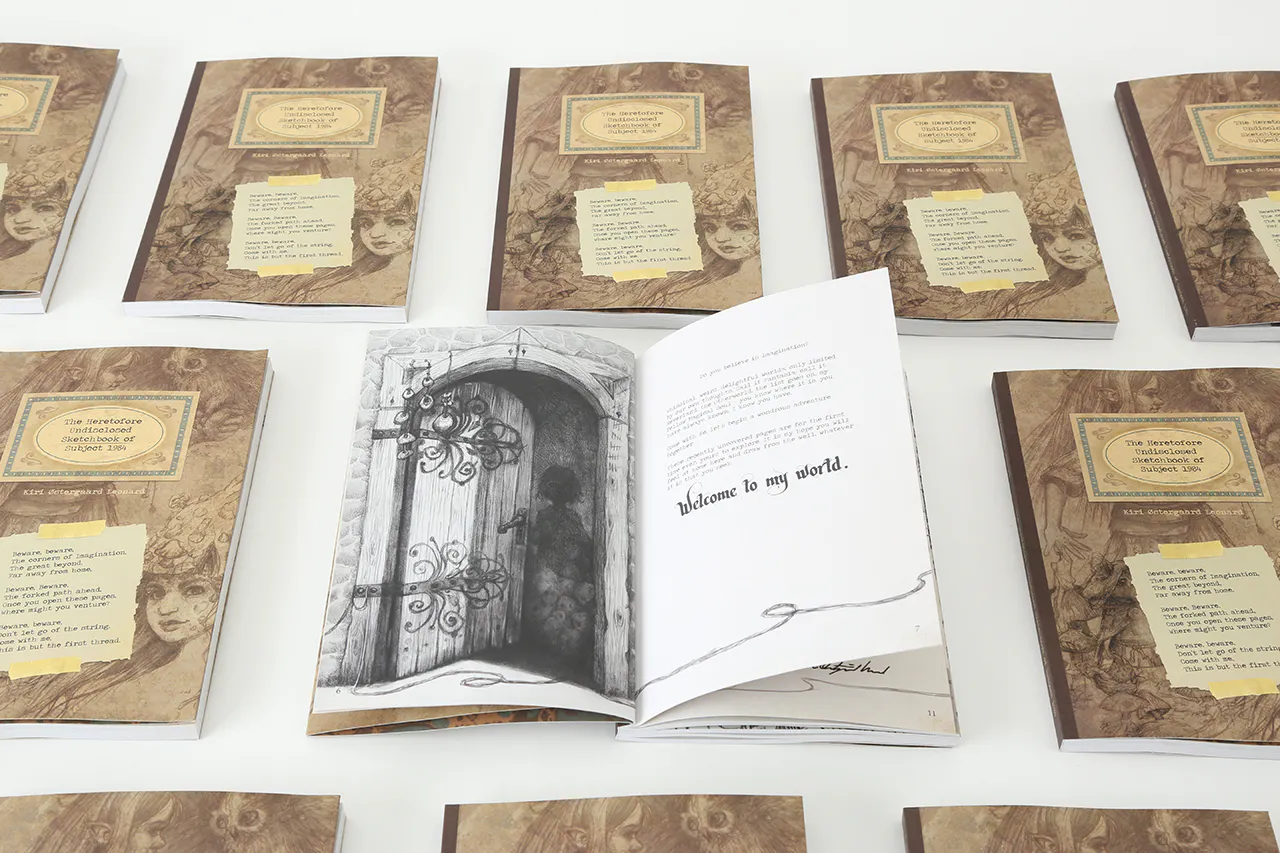 A sketchbook laying open to an illustration of a person walking through a wooden door and Welcome to My World.