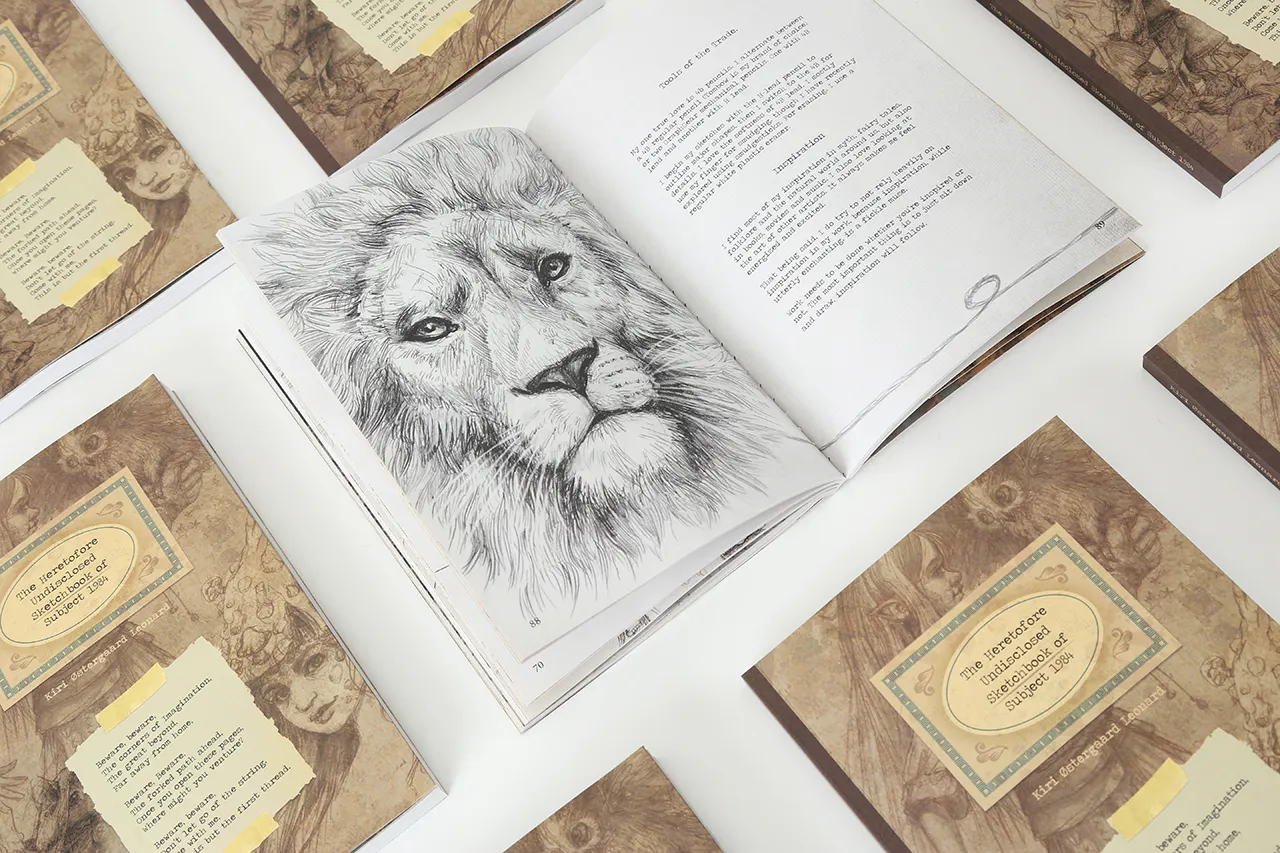 Custom printed sketchbooks lined up in rows with one open to an illustration of a lion in black and white.