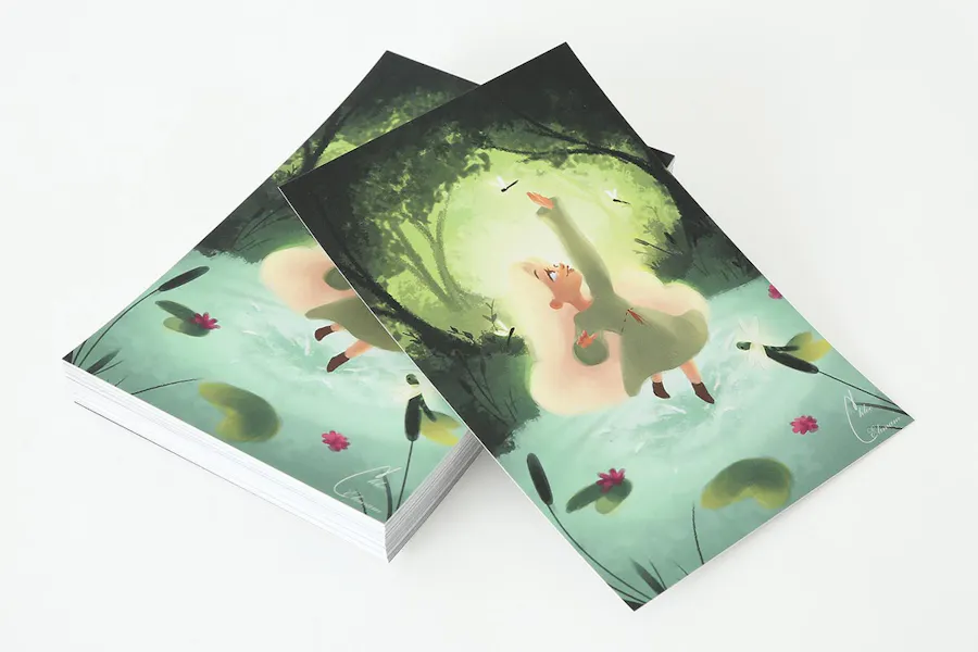 A stack of custom postcards printed with an illustration of a girl in a forest and Soft Touch laminate.