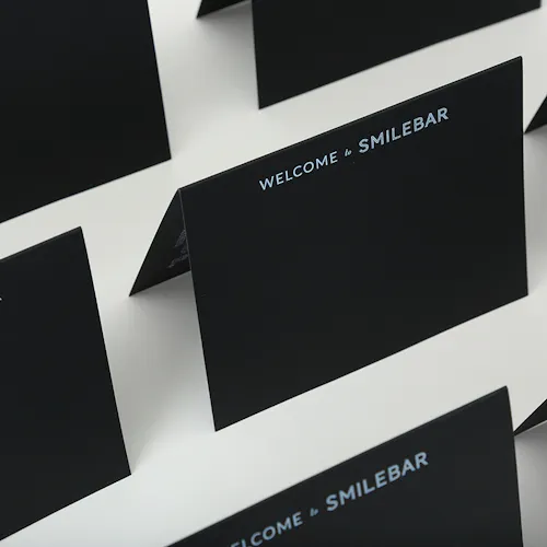 Custom cards lined up in rows printed on black paper stock with Welcome to Smilebar in white ink.