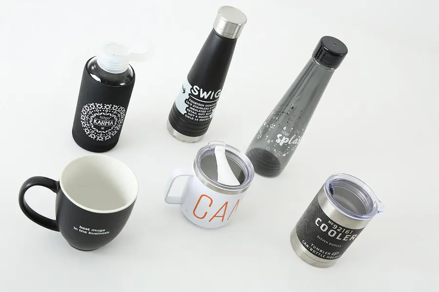 Three water bottles, a coffee mug and two tumblers printed with brand names, slogans and designs.