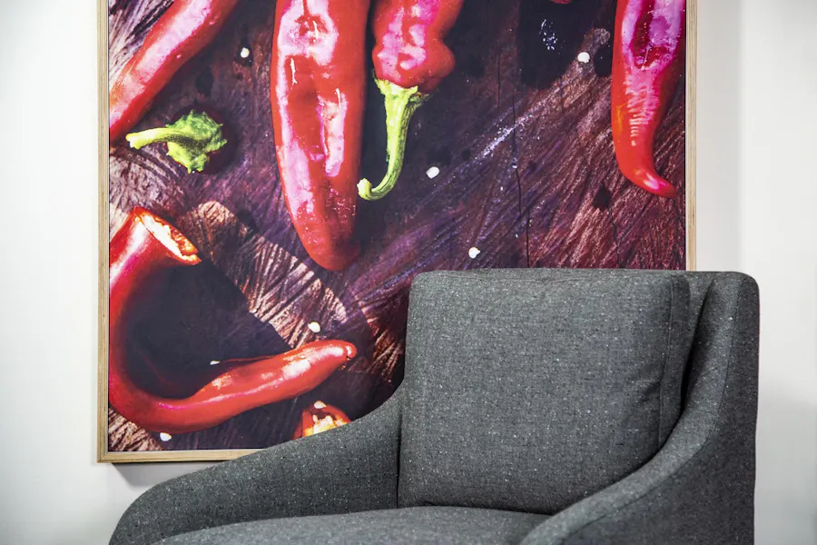 A gray chair in an office lobby with an SEG printed with red peppers hanging behind it.