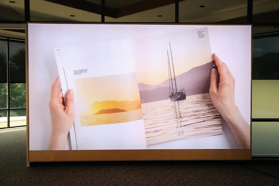 A backlit SEG of two hands holding open a booklet displayed in an office.